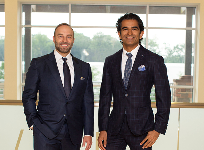 Surgeons Dr. Kortesis and Dr. Bharti in suits smiling in the waiting room of H/K/B Cosmetic Surgery