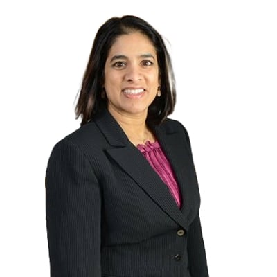 Professional headshot: woman in a dark blazer with a magenta blouse, smiling against a white background.