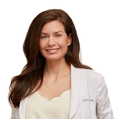 Smiling female doctor in a white coat against a white background.