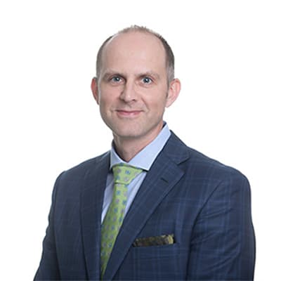 Professional head-and-shoulders portrait of a man in a blue checkered suit, light blue shirt, and lime green tie
