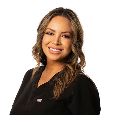 Smiling woman with wavy light-brown hair in a black top, portrait against a white background.