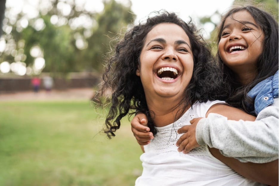 A mother playing with her daughter outside.